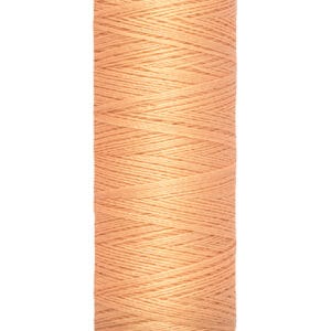 A spool of Gütermann sewing thread in a light peach color, labeled 100 meters and 110 yards. It has a cream-colored base and top.