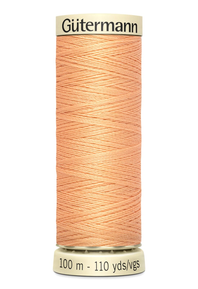 A spool of Gütermann sewing thread in a light peach color, labeled 100 meters and 110 yards. It has a cream-colored base and top.