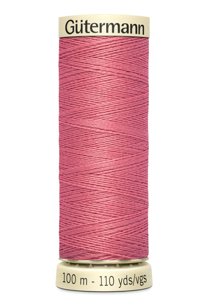 A spool of Gütermann thread in dusty pink, labeled 100 meters and 110 yards, with cream-colored ends.