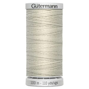 A cream-colored spool of Gütermann thread is displayed upright. The label on the spool indicates it's 100 meters or 110 yards long. The thread is tightly wound, showcasing its smooth texture.