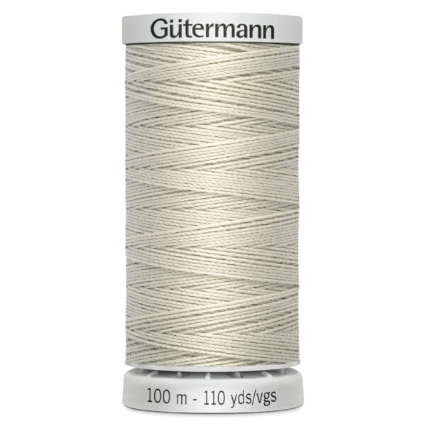A cream-colored spool of Gütermann thread is displayed upright. The label on the spool indicates it's 100 meters or 110 yards long. The thread is tightly wound, showcasing its smooth texture.