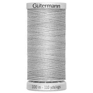 A spool of Gütermann thread in light gray. The label on top displays the brand name, and the bottom indicates the length as 100 meters or 110 yards. The thread is neatly wrapped around the spool.