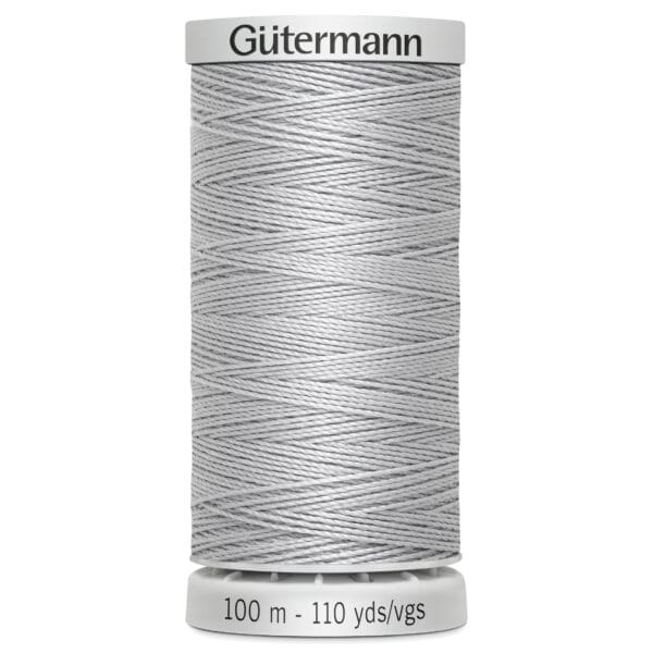 A spool of Gütermann thread in light gray. The label on top displays the brand name, and the bottom indicates the length as 100 meters or 110 yards. The thread is neatly wrapped around the spool.