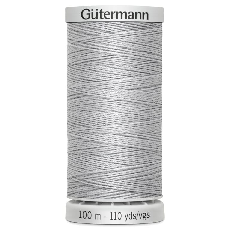 A spool of Gütermann thread in light gray. The label on top displays the brand name, and the bottom indicates the length as 100 meters or 110 yards. The thread is neatly wrapped around the spool.