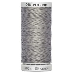 A spool of Gütermann thread in grey color, with a label indicating 100 meters or 110 yards. The spool is cylindrical, featuring a textured surface of tightly wound thread, and has white top and base caps with brand and measurement information.