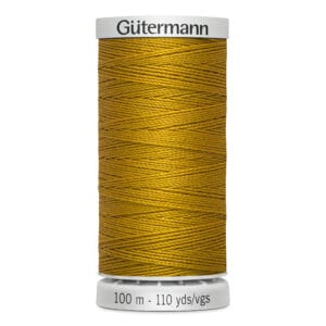 A spool of Gütermann thread in gold color. The spool is labeled with "100 m - 110 yds/vgs" and features a white base and top. The thread is neatly wound around the spool, showcasing its vibrant hue.
