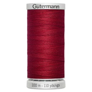 A spool of Gütermann thread in deep red, labeled with "100 m - 110 yds/vgs" at the base. The thread is tightly wound around the spool, displaying a smooth texture and rich color.