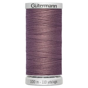 A spool of Gütermann thread in a dusty purple color. The spool indicates it contains 100 meters or 110 yards of thread. The top and bottom of the spool are light gray with the brand name printed on the top.