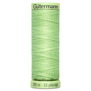 A spool of Gütermann sewing thread in light green, labeled with "30 m - 33 yds/vgs" on the bottom. The thread is tightly wound in a crisscross pattern around the spool.