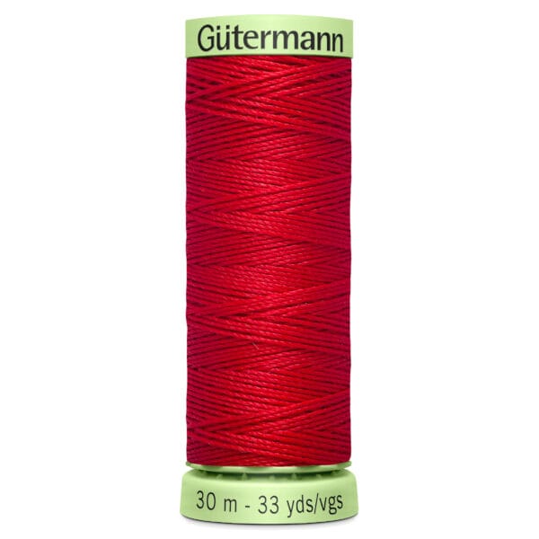 A spool of Gütermann red sewing thread, labeled with 30 meters or 33 yards. The spool has a light green cap and base with the brand name and measurements printed on it.