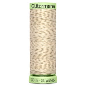 A spool of Gütermann cream-colored cotton sewing thread, 30 meters (33 yards) long, with a light green label on top and bottom. The thread is neatly wound around the spool in a crisscross pattern.