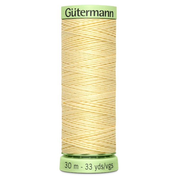 A spool of Gütermann thread, pale yellow in color, with 30 meters or 33 yards length indicated on the bottom. The thread is wrapped neatly around a light green spool.