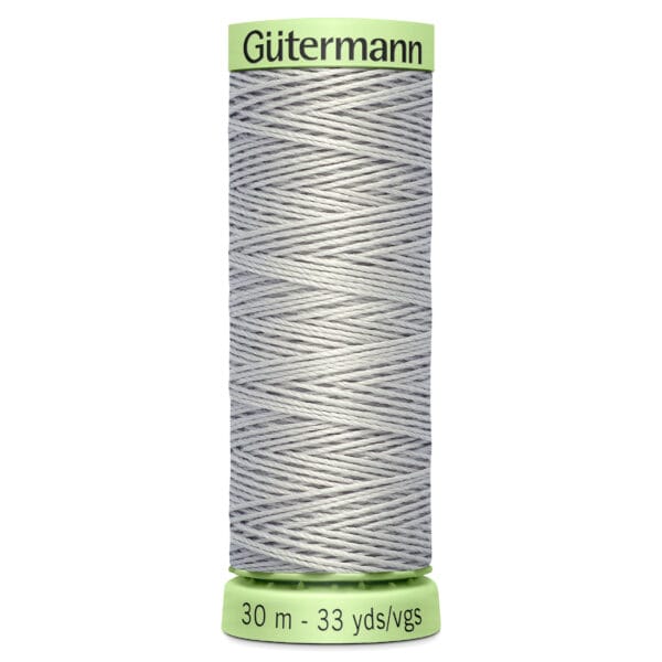 A spool of Gütermann thread in light gray, with a green top and bottom. The label shows "30 m - 33 yds/vgs" indicating the length of the thread.