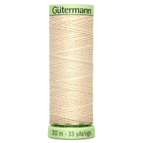 A spool of Gütermann cream-colored thread with a green top and bottom. The label indicates 30 meters or 33 yards of thread.