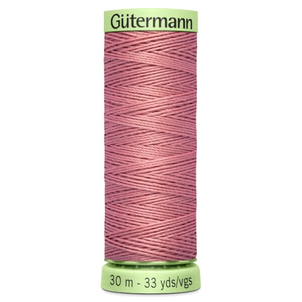 A spool of Gütermann thread with a pink thread wrapped around it. The spool displays "Gütermann" at the top and "30 m - 33 yds/vgs" at the bottom on a light green label.