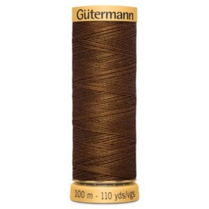 A spool of brown Gütermann sewing thread is vertically placed. The label reads "Gütermann" at the top and "100 m - 110 yds" at the bottom. The thread is tightly wound in a zigzag pattern.