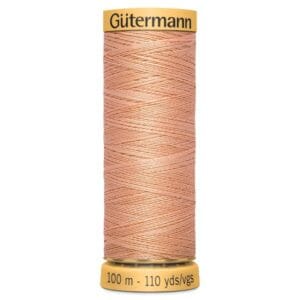 A spool of Gütermann thread featuring light peach-colored thread wound neatly. The spool has labels indicating it contains 100 meters or 110 yards of thread.