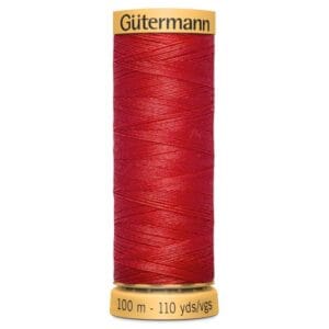 A spool of Gütermann red thread labeled "100 m - 110 yds." The spool has a yellow top and bottom, with the brand name printed at the top. The thread is wrapped neatly around the spool.