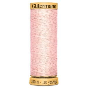 A spool of Gütermann pink sewing thread is shown. The spool is labeled with a yellow cap and base, indicating a length of 100 meters or 110 yards. The thread is neatly wound around the spool.