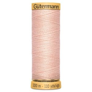 A spool of Gütermann cotton sewing thread in a light pink color, labeled "100 m - 110 yds" on the bottom. The spool has a beige cap with the brand name written on it.
