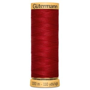 A spool of Gütermann red sewing thread, with 100 meters (110 yards) indicated on the base. The spool has a gold top and base, featuring the brand name in black text on the top.