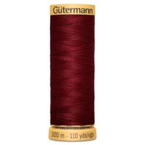 A spool of Gütermann thread in dark red. The label on the top reads "Gütermann" and the bottom indicates "100 m - 110 yds/vgs." The thread is tightly wound around the spool.