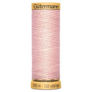 A spool of Gütermann sewing thread, 100 meters (110 yards), in light pink. The spool has a yellow top and bottom, with the brand name on the top and length measurement on the bottom. The thread is neatly wound.