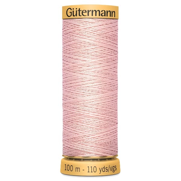 A spool of Gütermann sewing thread, 100 meters (110 yards), in light pink. The spool has a yellow top and bottom, with the brand name on the top and length measurement on the bottom. The thread is neatly wound.