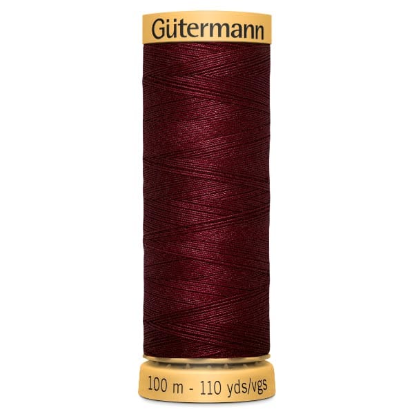 A spool of Gütermann thread in deep red, wrapped around a beige holder. The label indicates 100 meters or 110 yards. The thread appears smooth and finely wound.