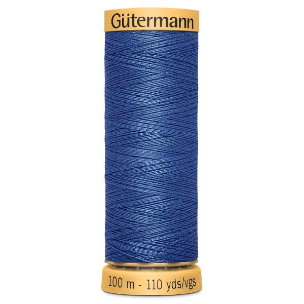 A spool of Gütermann thread shows tightly wound blue thread. The label indicates 100 meters or 110 yards. The spool is cylindrical with yellow ends, and the thread is neatly arranged in a crisscross pattern.