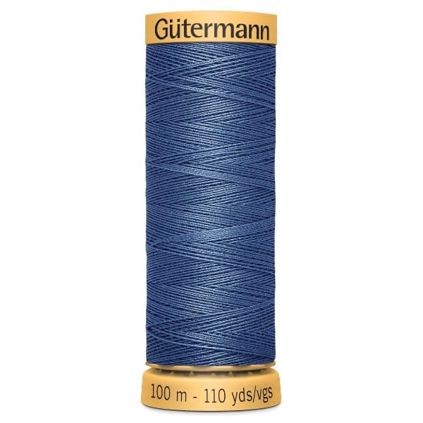 A spool of Gütermann blue sewing thread. The label on the top reads "Gütermann," and the label on the bottom indicates "100 m - 110 yds/vgs." The thread is neatly wound around the spool.