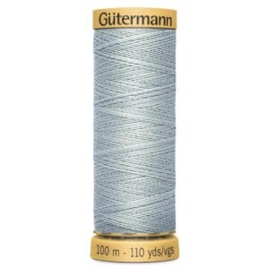 Spool of Gütermann thread with light blue color. The label shows 100 meters and 110 yards. The spool is gold-colored at the ends with black text on it.