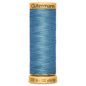 A spool of Gütermann blue thread with a yellow label on top and bottom. The label reads "Gütermann" on the top and "100 m - 110 yds/vgs" on the bottom. The thread is tightly wound and has a shiny texture.