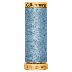 A spool of Gütermann sewing thread in light blue, with a capacity of 100 meters or 110 yards. The top and bottom of the spool are yellow with black text indicating the brand and length.