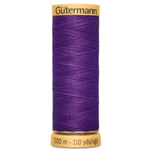 Spool of Gütermann thread in royal purple, with a golden cap and base. Label reads "100 m - 110 yds/vgs".
