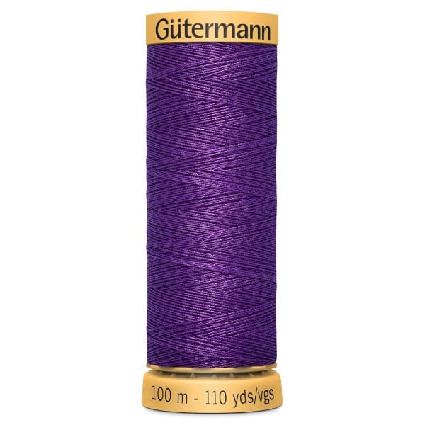 Spool of Gütermann thread in royal purple, with a golden cap and base. Label reads "100 m - 110 yds/vgs".