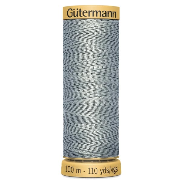 A spool of Gütermann sewing thread in a light grey color. The label reads "100 m - 110 yds." The spool has a yellow top and bottom, showcasing a neatly wound, shiny thread.