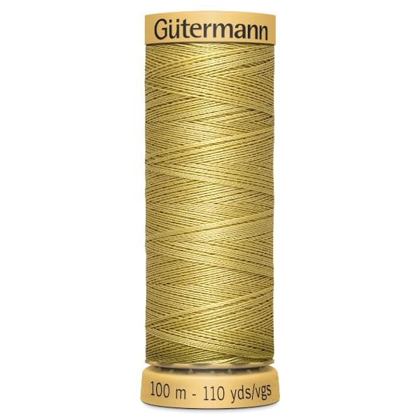 A spool of Gütermann gold thread is vertically oriented against a white background. The label indicates it contains 100 meters or 110 yards of thread. Patterns of crisscrossed thread are visible on the spool.