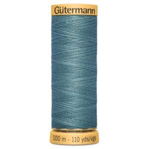 A spool of Gütermann sewing thread in a teal color, showing 100 meters or 110 yards on the label. The thread is neatly wound in a zigzag pattern and the spool has a yellow top and bottom.