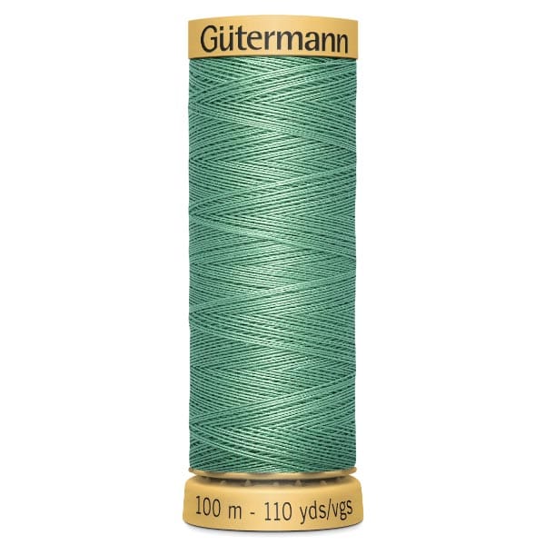 A spool of Gütermann green sewing thread, measuring 100 meters or 110 yards, on a yellow base. The thread is wound neatly in a crisscross pattern.