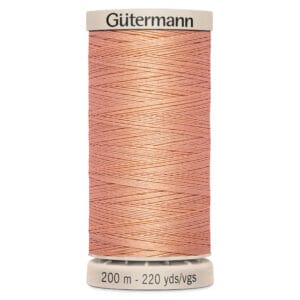 A spool of Gütermann thread in coral pink, labeled with "200 m - 220 yds/vgs" at the base. The thread is wound neatly around the spool.
