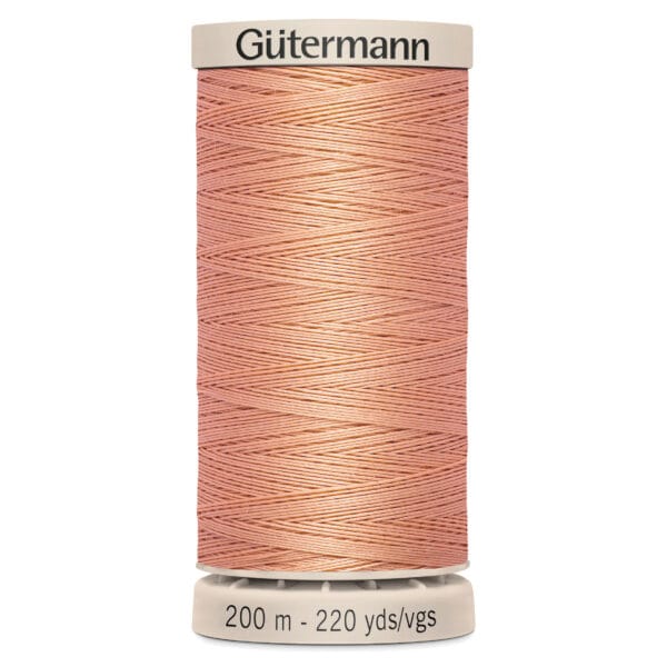 A spool of Gütermann thread in coral pink, labeled with "200 m - 220 yds/vgs" at the base. The thread is wound neatly around the spool.