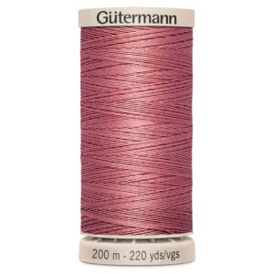 A tan spool labeled "Gütermann" holds pink thread wound neatly around it. The base reads "200 m - 220 yds/vgs.