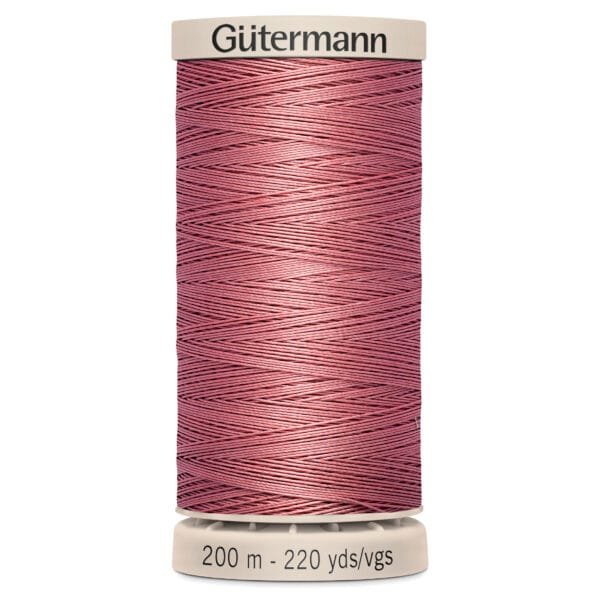 A tan spool labeled "Gütermann" holds pink thread wound neatly around it. The base reads "200 m - 220 yds/vgs.