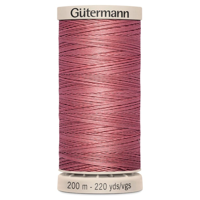 A tan spool labeled "Gütermann" holds pink thread wound neatly around it. The base reads "200 m - 220 yds/vgs.