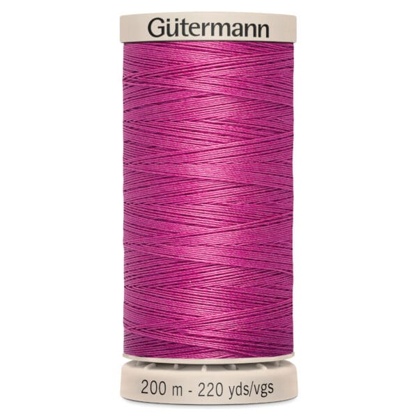 A spool of Gütermann thread in vibrant magenta. The spool features white caps on the top and bottom, with labeling indicating the thread length as 200 meters or 220 yards.