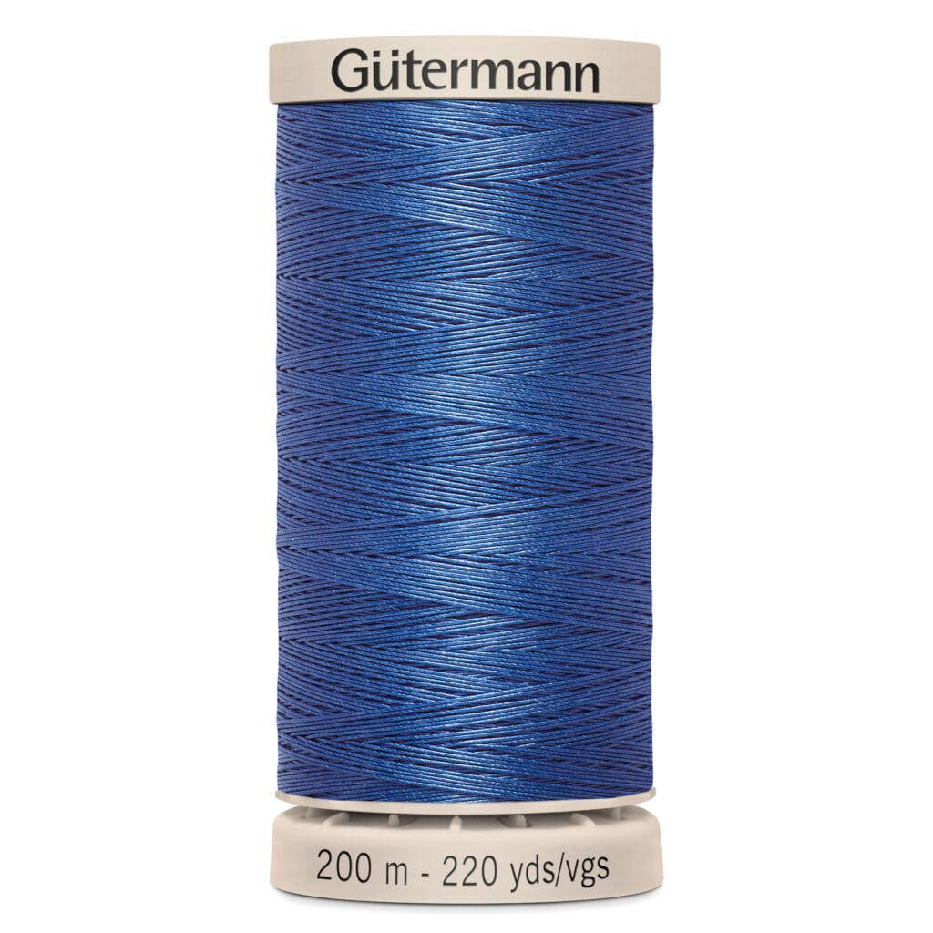 A spool of Gütermann thread stands upright. It is vibrant blue, with the label indicating it contains 200 meters (220 yards) of thread. The brand name is printed in black on the top edge of the spool.