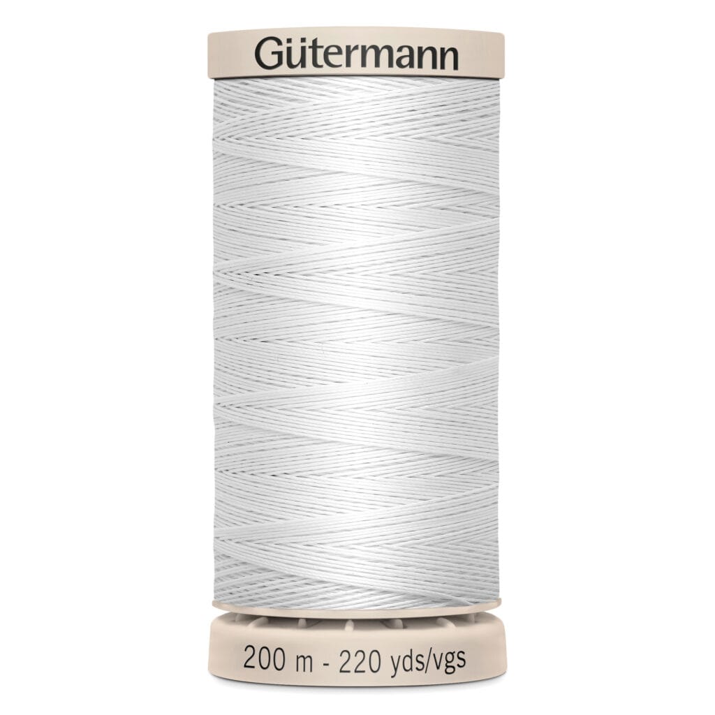 A spool of Gütermann white sewing thread, labeled with "200 m - 220 yds/vgs," stands vertically. The spool has a beige top and bottom with the brand name "Gütermann" printed on the top.