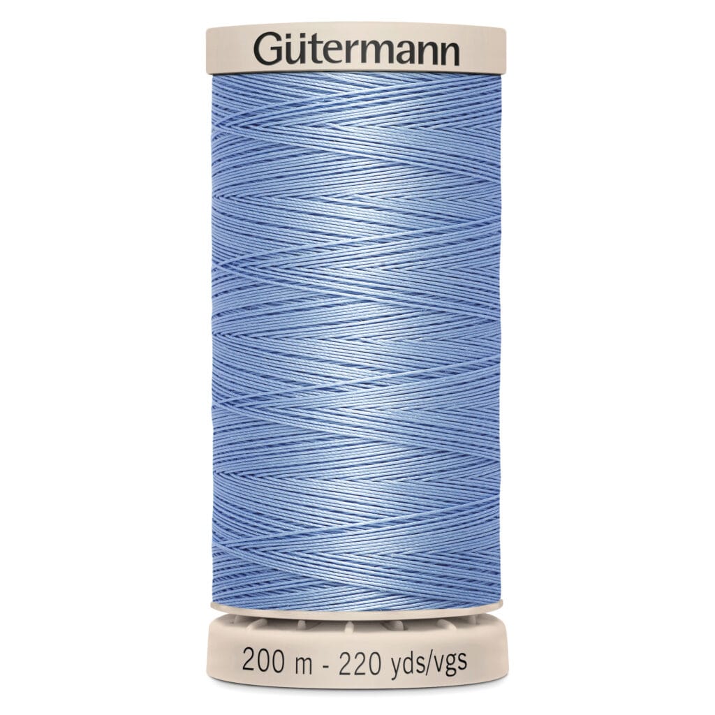 A spool of blue Gütermann thread is shown vertically, wrapped neatly around a beige base. The label reads "200 m - 220 yds/vgs.