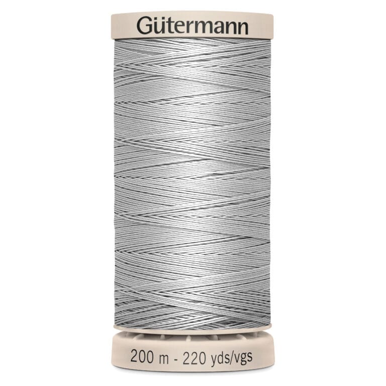 A spool of Gütermann sewing thread in a light gray color. The label on top is beige with the brand name, and the bottom label shows 200 meters or 220 yards of thread. The thread is neatly wrapped around the spool.